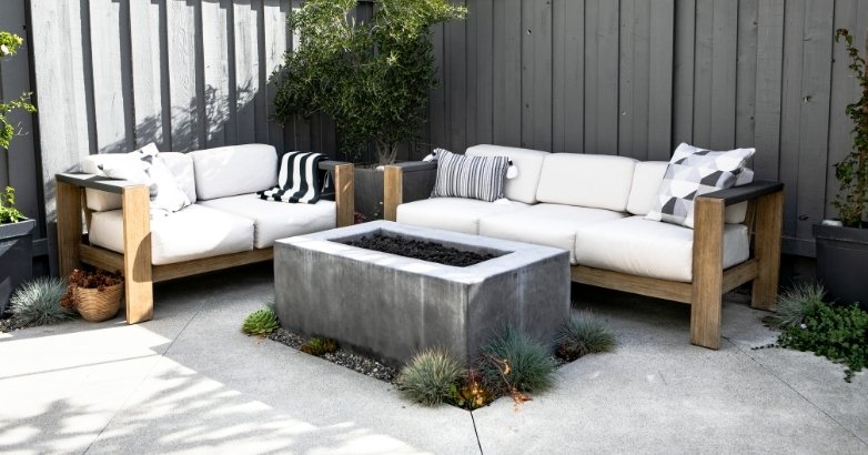 Poured concrete patio with modern seating and fire pit in minimalist backyard design