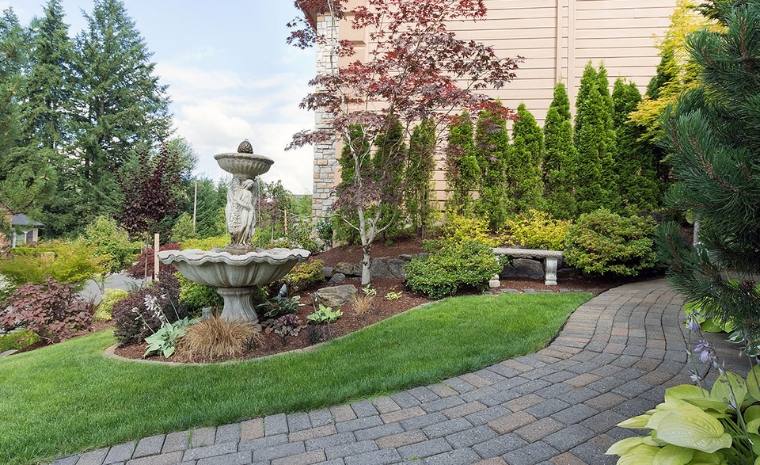 Curved paver walkway with landscaped backyard comfort and decorative garden fountain in Old Lyme CT