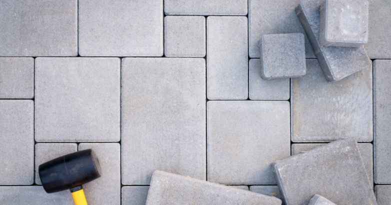A close-up image of interlocking concrete pavers arranged in a geometric pattern using rectangular and square gray blocks.