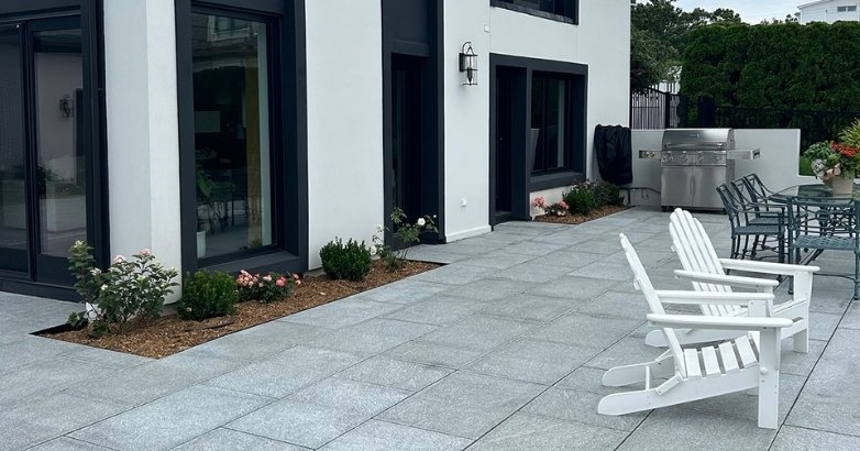 Modern granite patio with outdoor seating and clean concrete landscaping design.