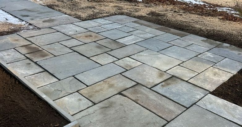 Durable natural stone patio with thermal finish and custom landscape paving design.