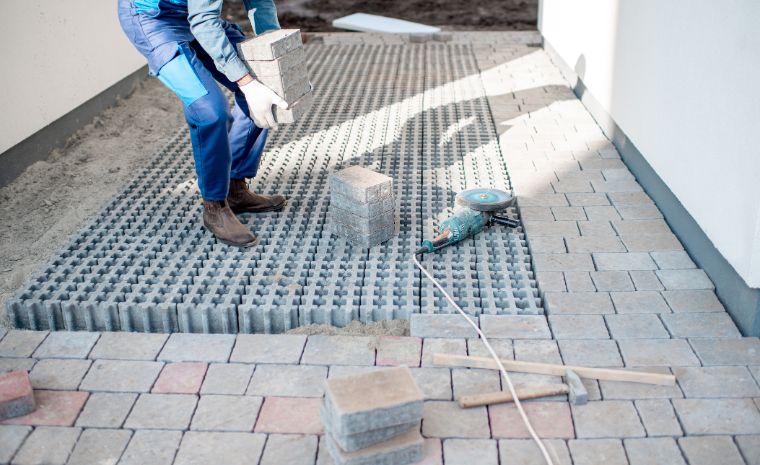 Contractor installing interlocking pavers over a prepared base for patio construction in Clinton CT