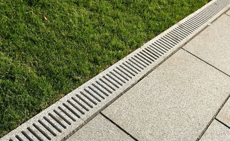 Linear patio drain beside bluestone pavers and green lawn in Essex, CT