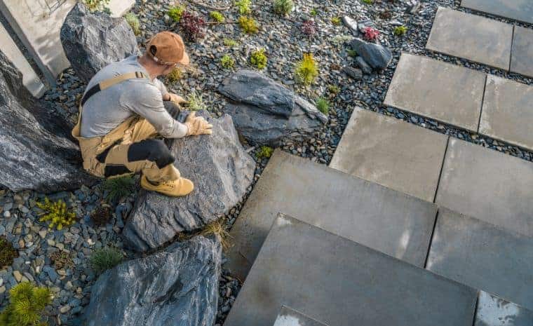 Landscaper positioning natural stone beside bluestone patio pavers in Essex, CT