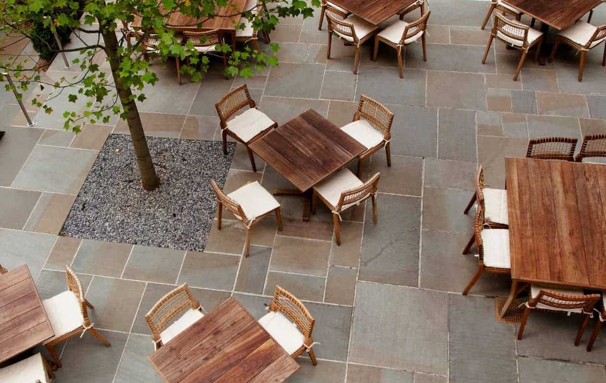 Bluestone patio with wooden dining tables and a mature shade tree in Killingworth, CT