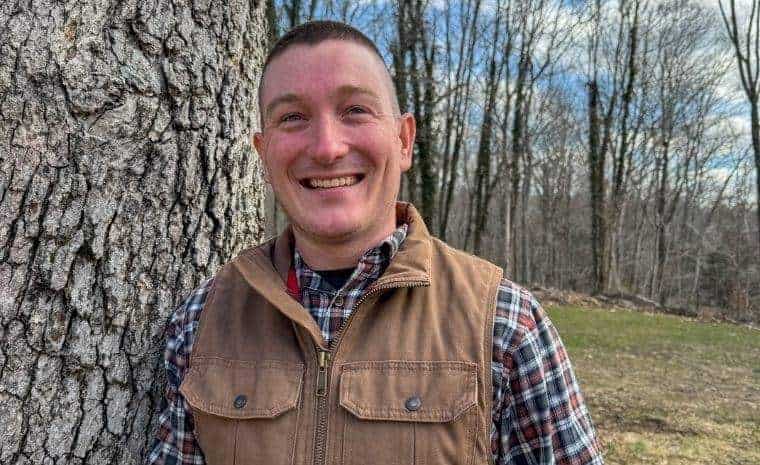 Smiling landscaping professional standing beside a mature tree in Killingworth, CT