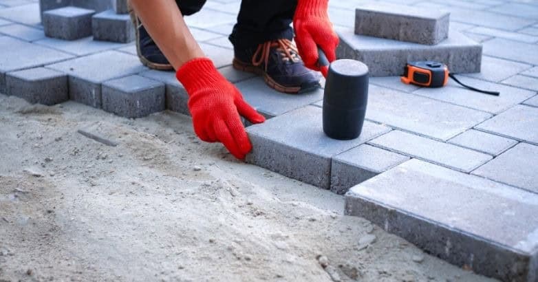 Contractor installing concrete pavers for a custom patio showcasing What’s the Cost of a Stone Patio in Connecticut