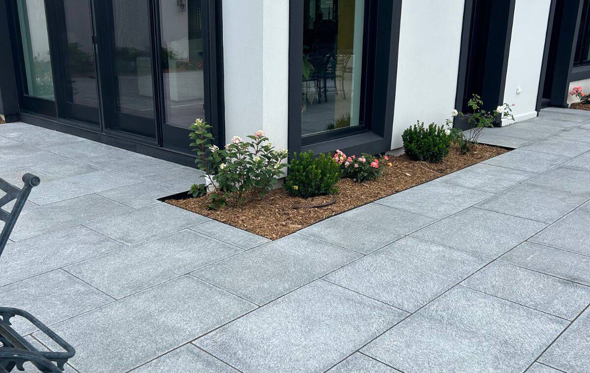 Granite stone patio with landscaped garden beds beside a modern Old Lyme CT home
